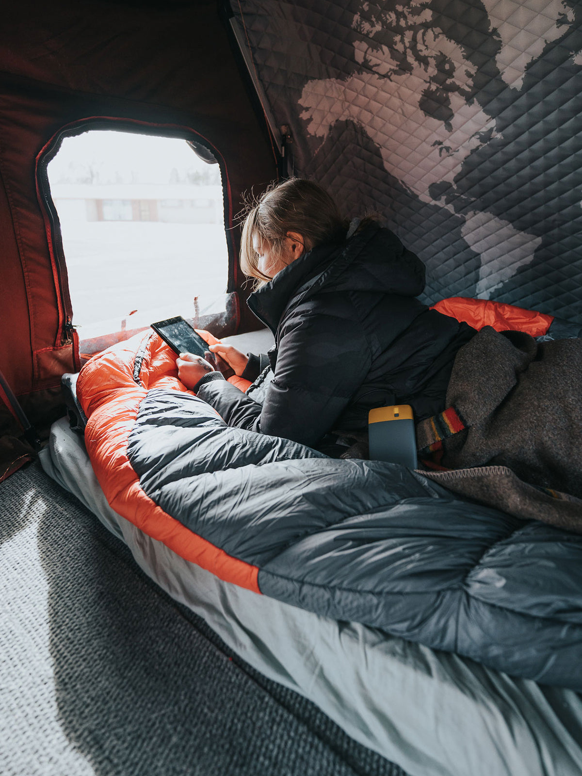 girl using tablet in tent connected to BioLite Power Bank Charge 40 PD