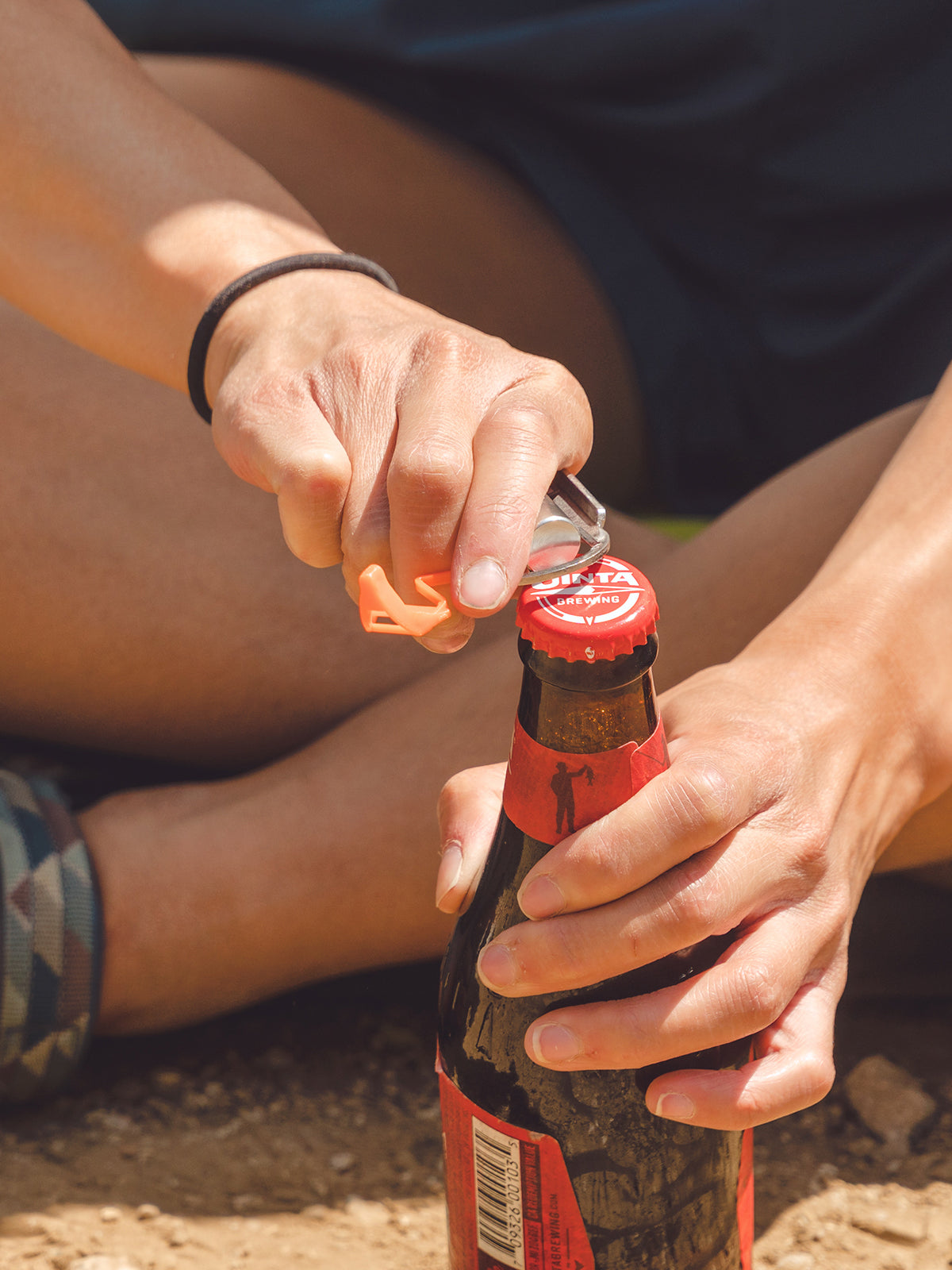 Jetboil CrunchIt Fuel Can Recycling Tool being used to open bottle