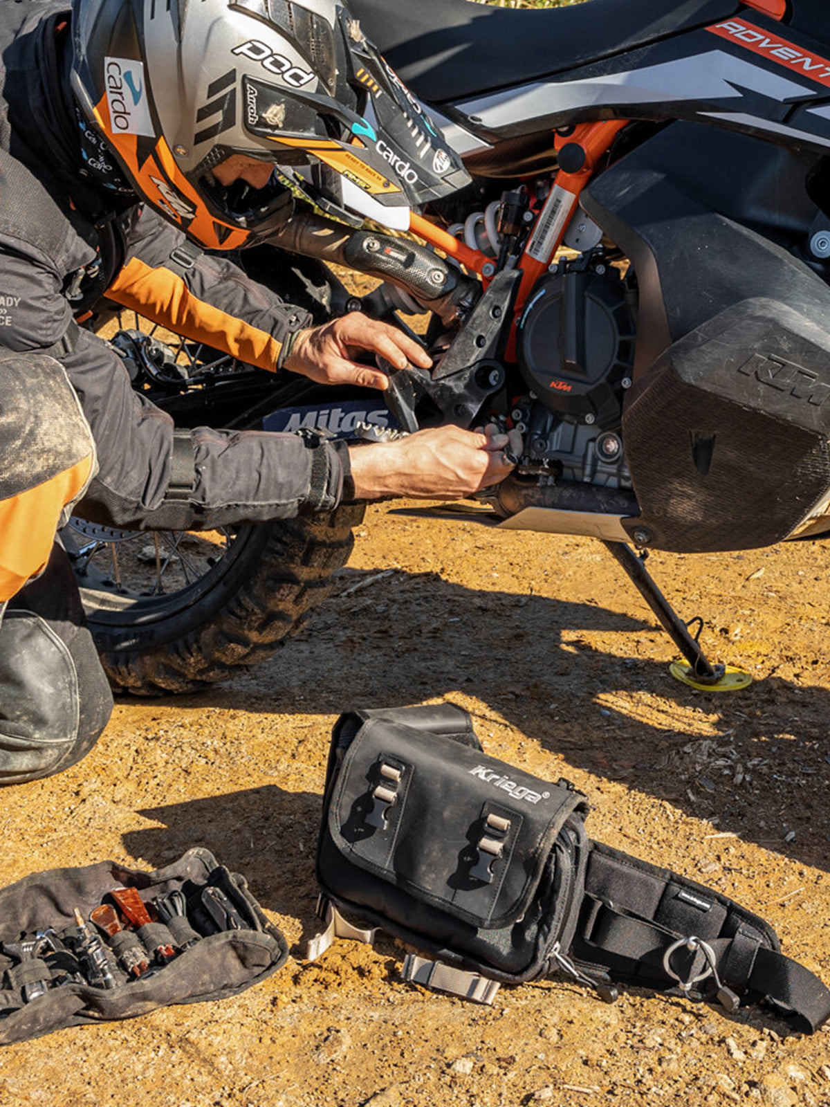 motorbike rider fixing his bike with the Kriega R8 Waist Pack on the ground