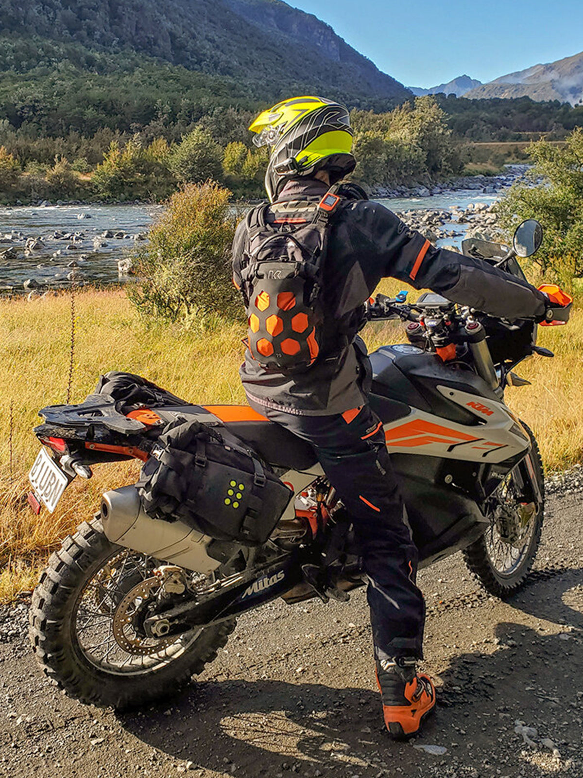 motorcycle rider wearing Kriega Trail9 Adventure Backpack next to a river